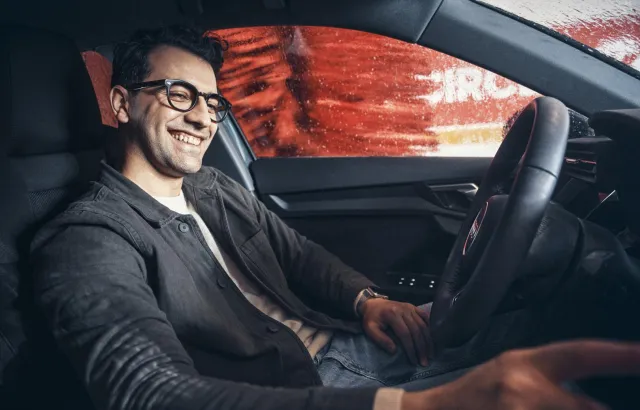 Man smiling in his car, while it is washed